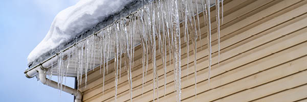 Icicles hang down from the edge of a roof.